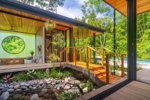 Modern Japanese-style home with pool surrounded by lush jungle greenery.