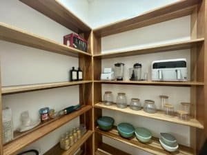 Spacious kitchen pantry with wooden shelves and organized jars and appliances.