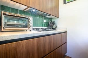 Contemporary kitchen with green tile backsplash, toaster oven, and countertop appliances.