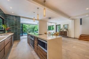 Modern kitchen and living area in rainforest home with pool view.