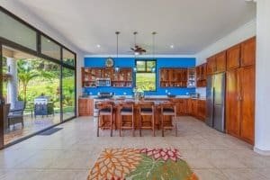 Spacious kitchen with wooden cabinets, large windows, and garden view in Dominical.