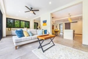 Bright living room with large windows, white sofa, and ceiling fan in Costa Rica.