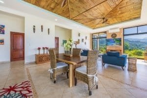 Bright living room with large windows overlooking lush green landscape and mountains.