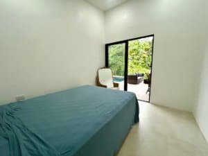 Bright bedroom with sliding glass door to outdoor pool area in Dominical.