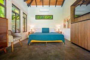 Bright bedroom with ocean view, modern decor, and large windows in Dominical.
