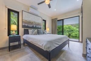 Modern bedroom with rainforest view, large windows, and stylish decor.