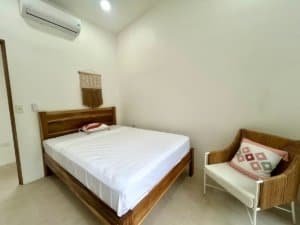 Bright bedroom with wooden bed frame and cozy armchair in Dominical.