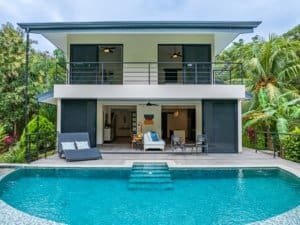 Modern rainforest home with pool, balcony, and lush tropical surroundings.