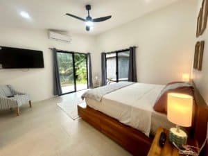 Spacious bedroom with large windows, modern decor, and pool view in Dominical.