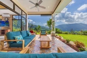 Covered patio with mountain view, outdoor seating, and lush garden.