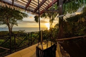Balcony with swing and hammock overlooking ocean at sunset in Dominical.