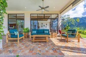 Covered outdoor living space with mountain view, comfortable seating, and lush garden.