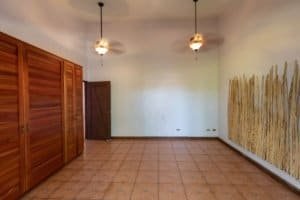 Empty room with wooden closet, ceiling fans, and textured wall in Dominical.