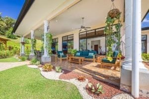 Covered patio with outdoor seating, lush garden, and hanging plants in Costa Rica.