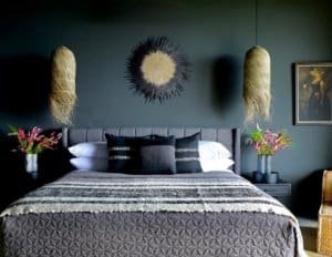 Elegant bedroom with dark green walls, black and white bedding, and wall art.
