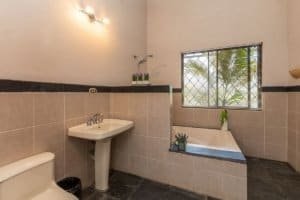 Bathroom with bathtub, sink, and window in Costa Rican home.