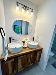 Contemporary bathroom with dual vessel sinks, wooden vanity, and modern lighting.