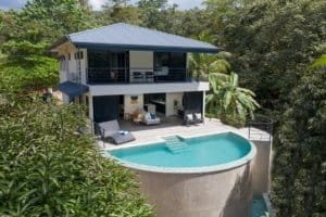 Modern rainforest home with pool, balcony, and lush tropical surroundings.