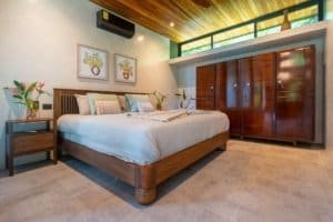Modern bedroom with wooden furniture and jungle view in Dominical, Costa Rica.