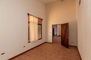 Empty room with window, door, and terracotta tile floor in Costa Rica.