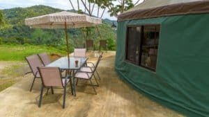 Outdoor patio with table, chairs, and umbrella near a green yurt in Dominical.
