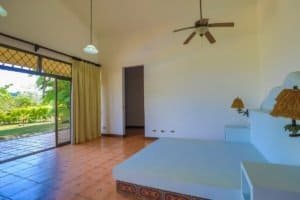 Bright bedroom with balcony, ceiling fan, and garden view in Costa Rica.