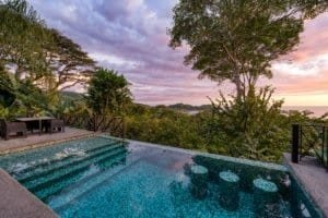 Luxury ocean view villa with pool, lush greenery, and sunset in Dominical, Costa Rica.