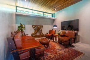 Stylish living room with leather furniture, large TV, and wooden ceiling in jungle home.