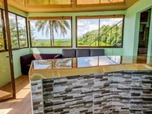 Living room with large windows showing lush jungle and mountain views in Dominical.