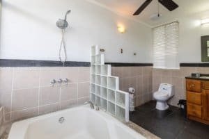 Bathroom with bathtub, toilet, and wooden cabinet in Costa Rica real estate.