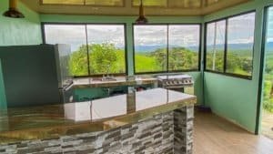 Bright kitchen with large windows overlooking lush jungle and mountains in Dominical.