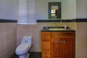 Bathroom with toilet, wooden vanity, mirror, and window in Costa Rica property.