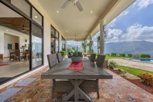 Covered outdoor dining area with mountain view and infinity pool in Costa Rica.