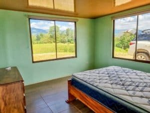 Bedroom with large windows overlooking lush jungle and mountain views in Dominical.