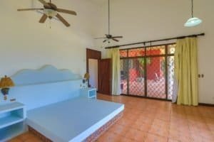Bright bedroom with ceiling fans and large sliding glass door with yellow curtains.