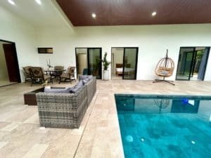 Spacious indoor living area with pool, outdoor seating, and hanging chair in Dominical.