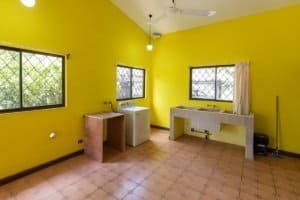 Vivid yellow room with windows, laundry area, and tiled floor in Costa Rica.