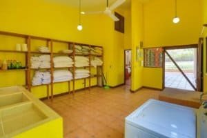 Colorful laundry room with yellow walls, shelves, and washing machine in Dominical.