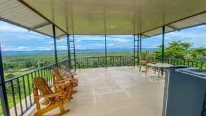 Spacious balcony with wooden chairs overlooking lush jungle and mountains.