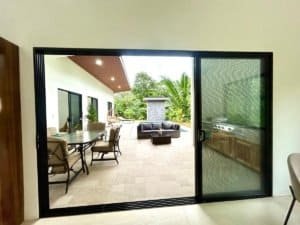 Spacious outdoor patio of a modern tropical home with pool and lush greenery.