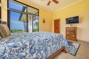 Bright bedroom with ocean view, large window, and modern decor in Dominical.