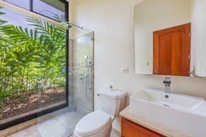 Bathroom with large window overlooking lush garden and walk-in shower.