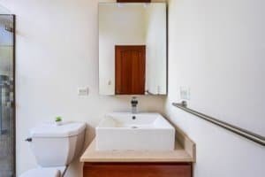 Bathroom with white sink, mirror, and wooden door in Costa Rica home.