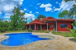 Beautiful hacienda style home with pool, lush greenery, and blue sky in Dominical.