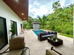 Luxury tropical home with pool, outdoor seating, and lush greenery.