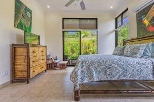 Spacious bedroom with ocean view, tropical garden, and modern decor in Dominical.