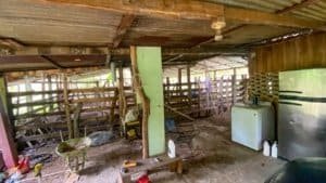 Interior of a rustic jungle cabin with wooden fencing and basic appliances.