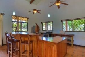 Spacious kitchen with wooden cabinets, bar stools, and ceiling fans in Dominical.