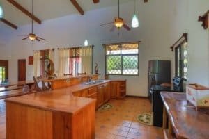 Interior of a Costa Rican home kitchen with wooden cabinets and large windows.