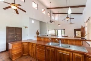 Bright kitchen with wooden cabinets, high ceilings, and ceiling fans in Costa Rica.